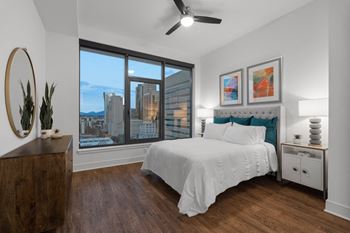 An apartment bedroom with a large window and a bed